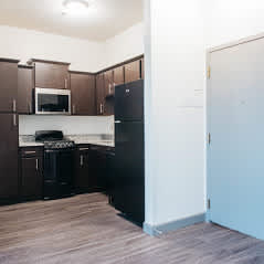 A kitchen with black appliances and brown cabinets.