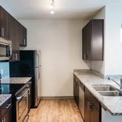 A kitchen with a black fridge and wooden floors.