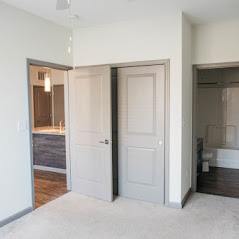 A white door is open to a room with a bed.