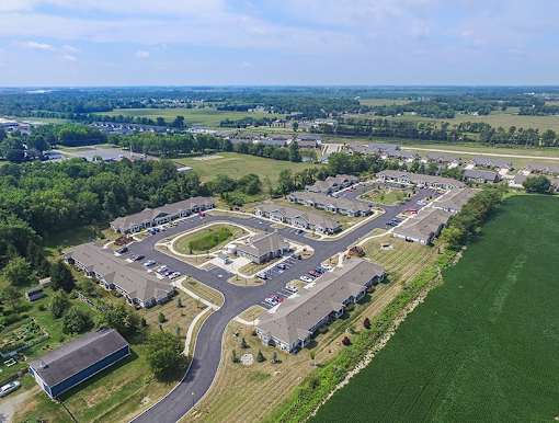 An aerial view of a large, open parking lot surrounded by buildings and green fields.