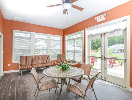 A patio with a table and chairs and a ceiling fan.