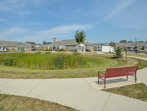 A bench sits on a sidewalk in front of a building.