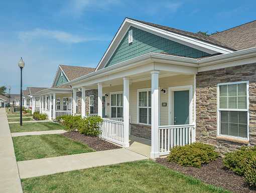 A row of houses with white porches and green roofs.