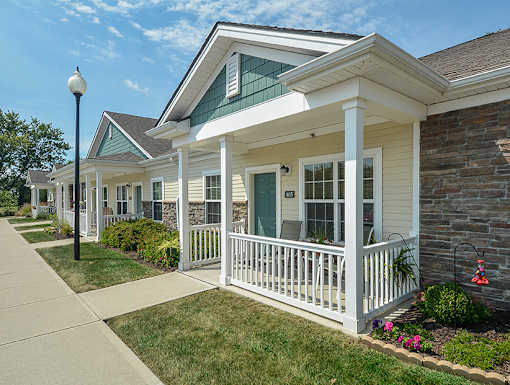 A white house with a porch and a green roof.