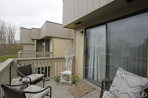 A balcony with a couch, chairs and a table.