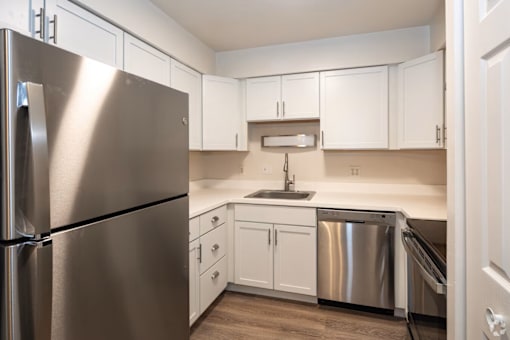 A kitchen with a stainless steel refrigerator and white cabinets.