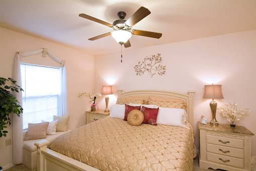 A bedroom with a bed, nightstands, and a ceiling fan.