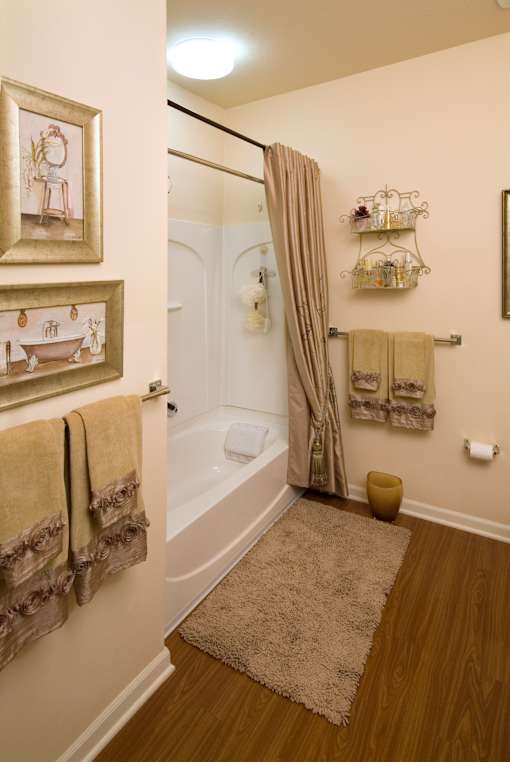 A bathroom with a tub, towel rack, and a rug.