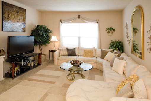A living room with a white couch, a coffee table, and a television.
