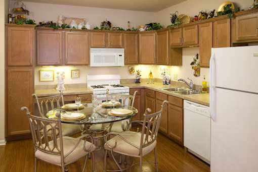 A kitchen with a table set for two and a white refrigerator.