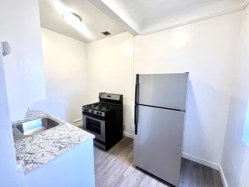 White kitchen featuring stainless steel refrigerator and stove