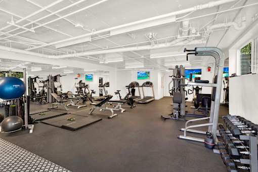 A spacious gym with a variety of equipment including treadmills, weights, and exercise balls at Westwood Riviera Apartments, Apartments, Los Angeles, CA