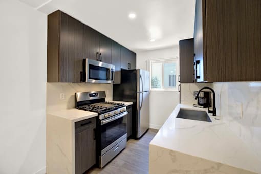 A modern kitchen with dark brown cabinets and white countertops at Westwood Riviera Apartments, Los Angeles, California