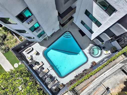 A swimming pool is surrounded by a concrete building at Westwood Riviera Apartments, Los Angeles, CA, 90024