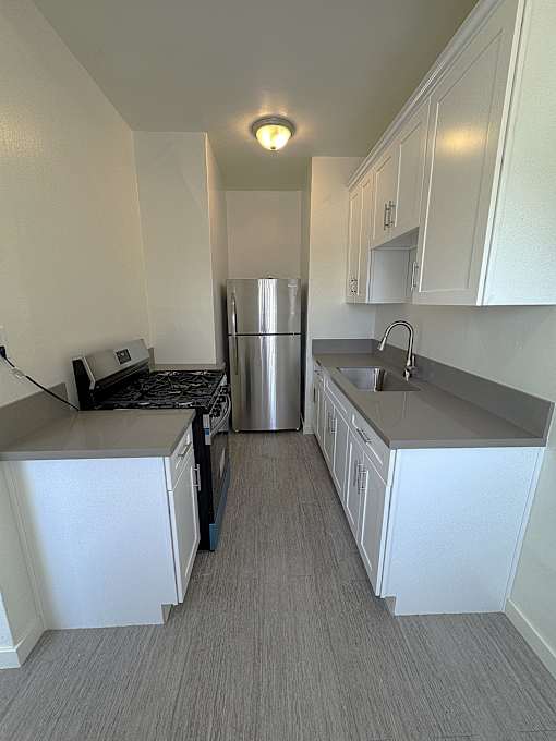 A kitchen with white cabinets and a stainless steel refrigerator.
