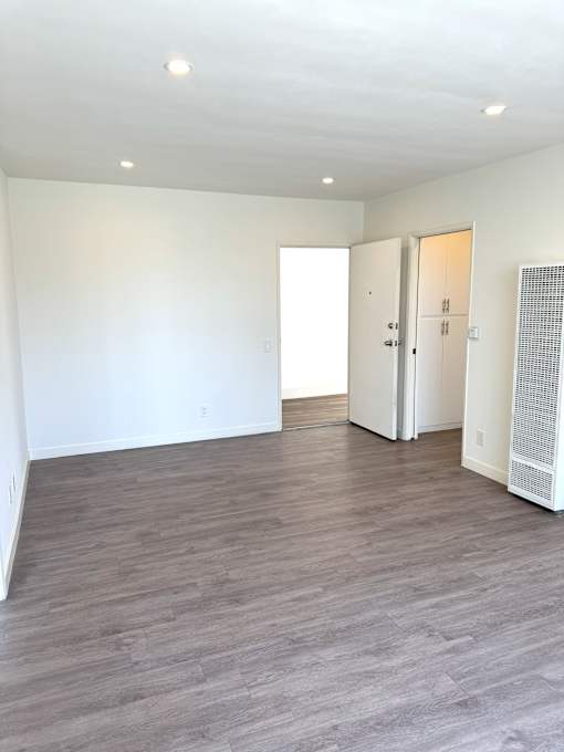 A room with a wooden floor and a white wall.
