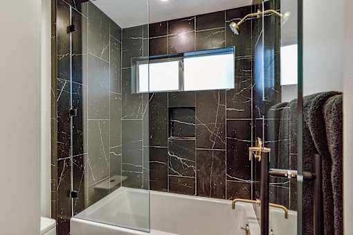 a bathroom with black tile and a shower and a tub at 8535 Colgate-Fully Furnished Apartments, Los Angeles, California