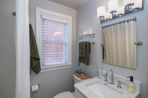 A bathroom with a white sink and a window with blinds.