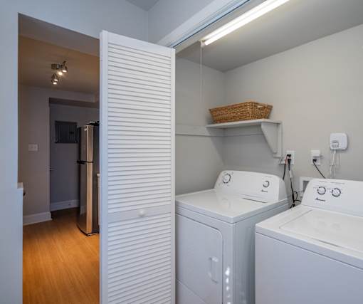 A laundry room with a basket on the shelf and two washing machines.
