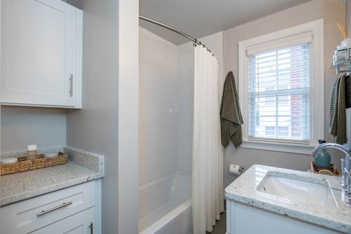 A bathroom with a white sink and a shower with a white curtain.