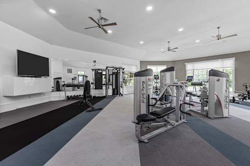 A spacious gym with a variety of equipment and a flat screen TV mounted on the wall.