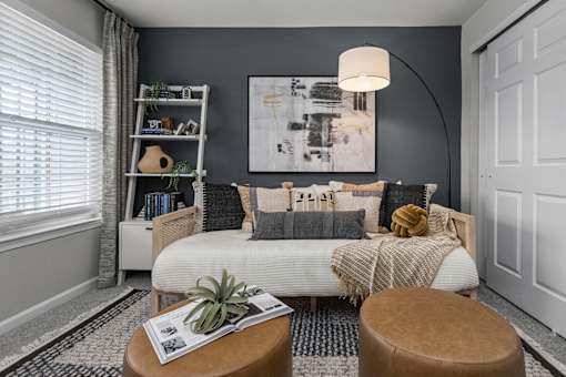 A cozy living room with a white sofa and a large abstract painting on the wall.