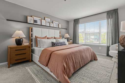 A bedroom with a large bed and a window with curtains.