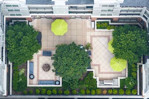 A courtyard with a fountain and umbrella-shaded seating areas.
