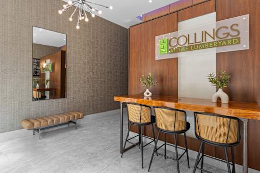 A conference room with a wooden table and chairs, a mirror, and a sign that reads "COLLINGS at the LUMBERYARD".