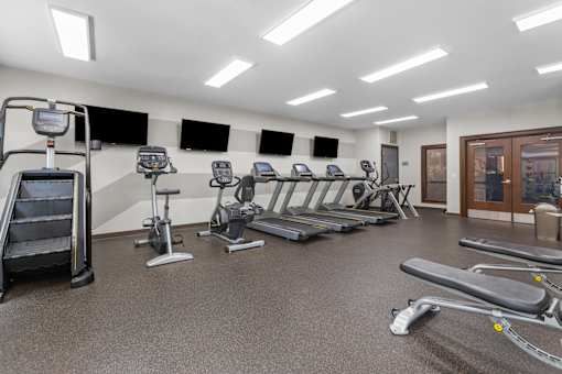 A gym with treadmills, elliptical machines, and a stair climber.