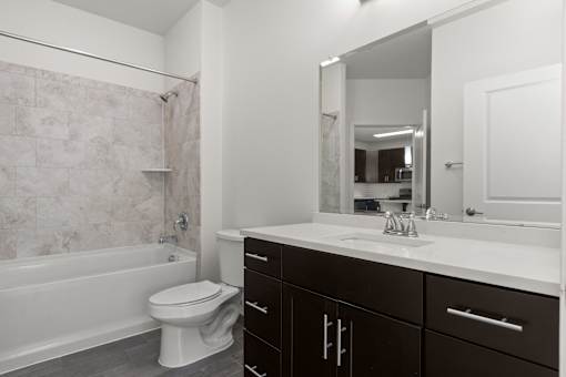 A white toilet sits in a bathroom next to a bathtub.