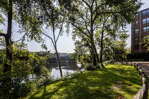 A serene park with a river and a bridge in the distance. at Merion Riverwalk Apartment Homes, Connecticut