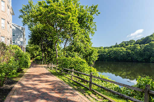 A pathway with a fence and a lake in the background. at Merion Riverwalk Apartment Homes, Shelton, CT