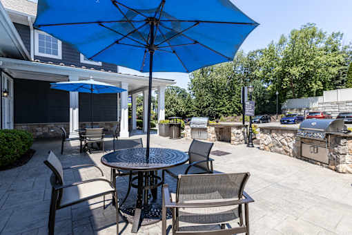 A blue umbrella is over a table with chairs.