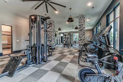 A well-equipped gym with a variety of exercise machines and a checkered floor.
