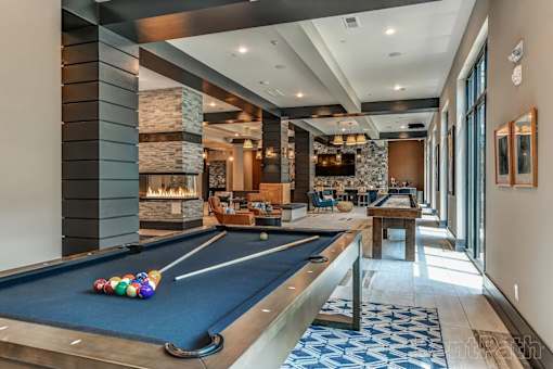 A pool table is in the middle of a room with a fireplace and a couch.