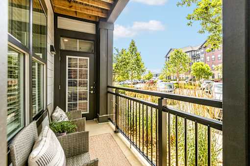 A balcony with a chair and a table with a potted plant on it.