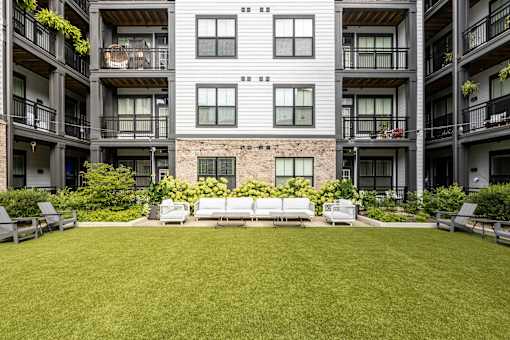 A large grassy area in front of a building with balconies.