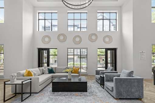 A modern living room with a grey sofa, a white couch, a coffee table, and a chandelier.