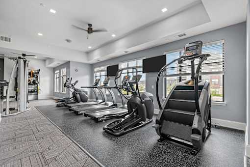 A gym with treadmills, elliptical machines, and a fan.