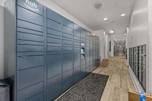 A long hallway with a row of blue lockers on the left and a row of white lockers on the right.