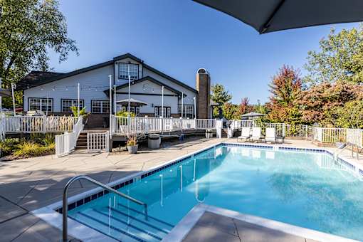 A swimming pool is surrounded by a white fence and a building.
