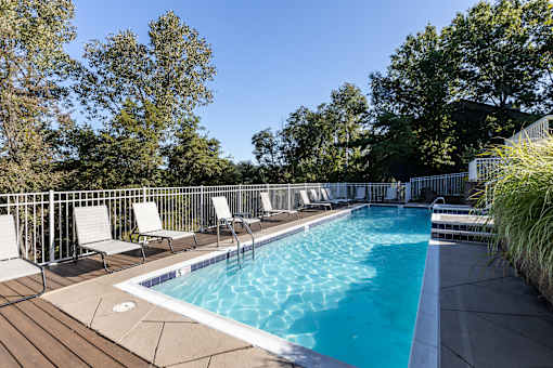 A pool surrounded by trees and chairs.