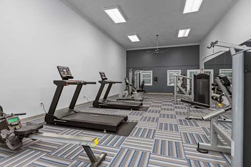 A gym with treadmills, elliptical machines, and other exercise equipment.
