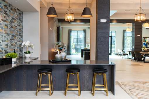 A bar area with three stools and a stone wall.