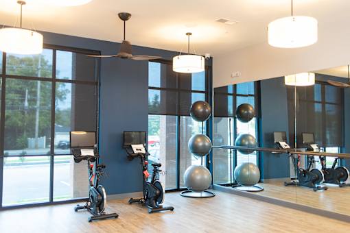 A gym with a row of exercise bikes and a row of silver balls.