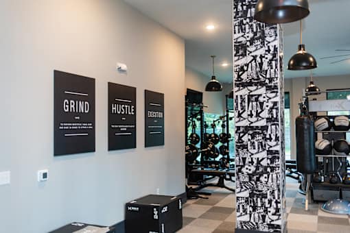 A gym with a wall of posters that say Grind, Hustle, and Elevate.