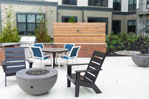 A patio with a fire pit and chairs.