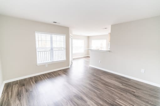 an empty living room with hardwood floors and a kitchen