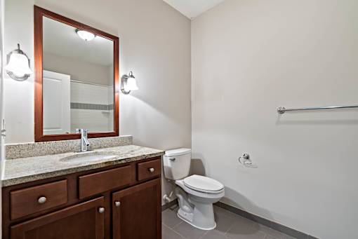 A bathroom with a toilet, sink, and mirror. at Pennsauken Golf Course Villas, PENNSAUKEN